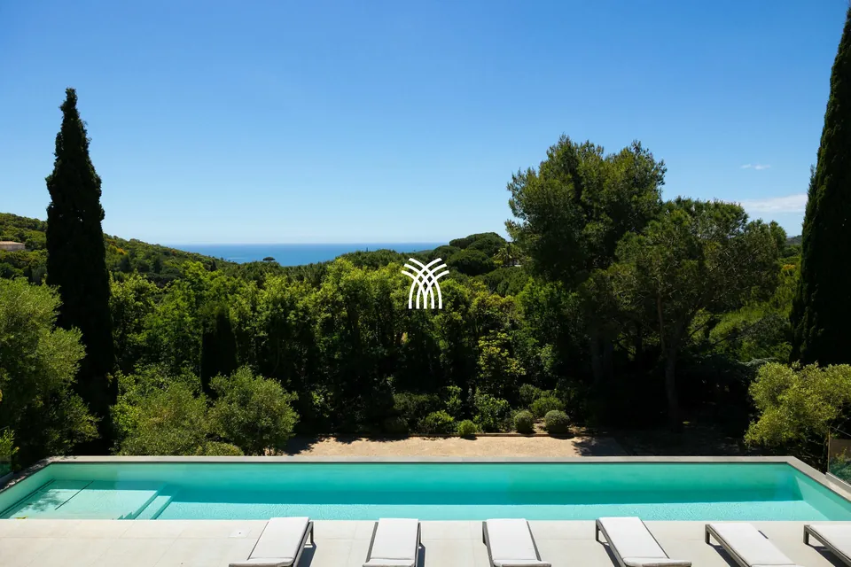 Long pool lined with cypress trees and a glimpse of the sea at Villa Texas, Ramatuelle